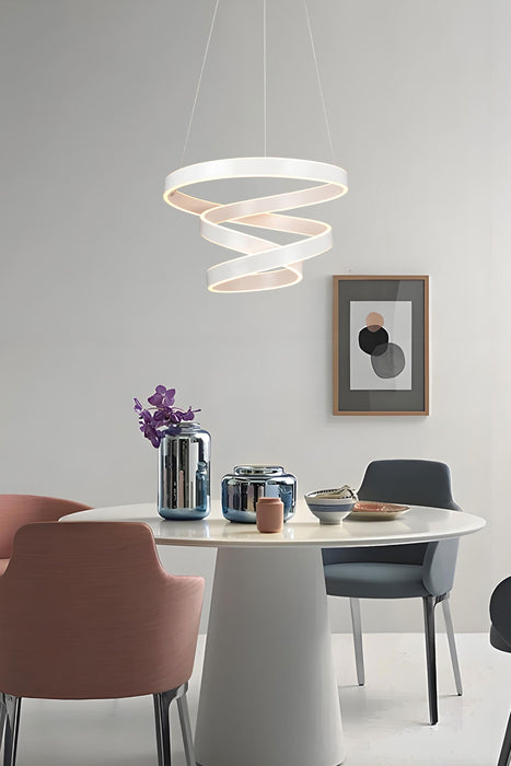 Modern dining room with a white spiral pendant light, round table, and colorful chairs.