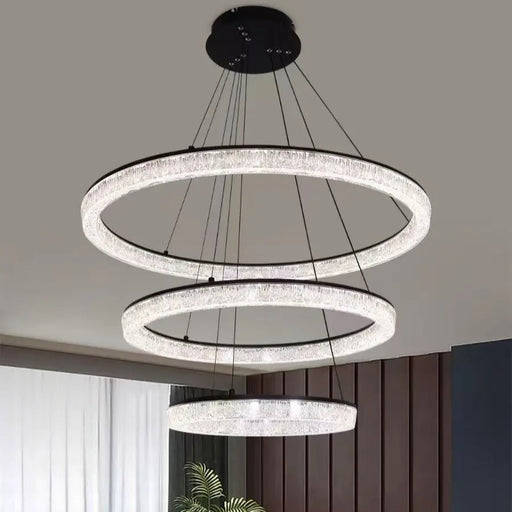 Modern chandelier with three circular lights in a living room setting.