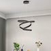 Modern dining room with a black spiral pendant light, round table, and gray chairs.