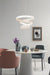 Modern dining room with a white spiral pendant light, round table, and colorful chairs.