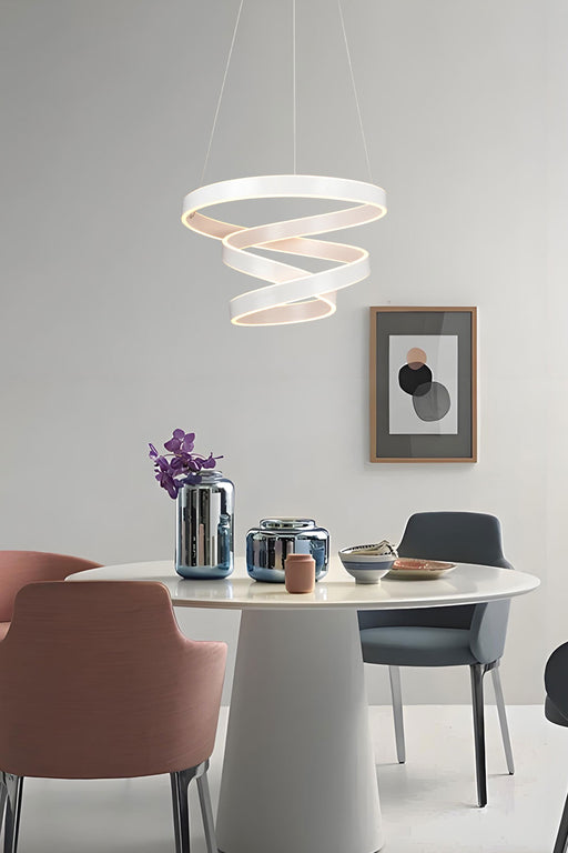 Modern dining room with a white spiral pendant light, round table, and colorful chairs.