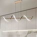 Modern pendant light fixture hanging above a dining table with marble backsplash.